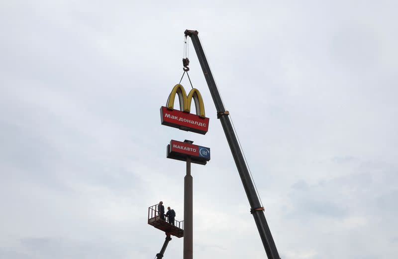 Workers remove the logo of McDonald's in Kingisepp