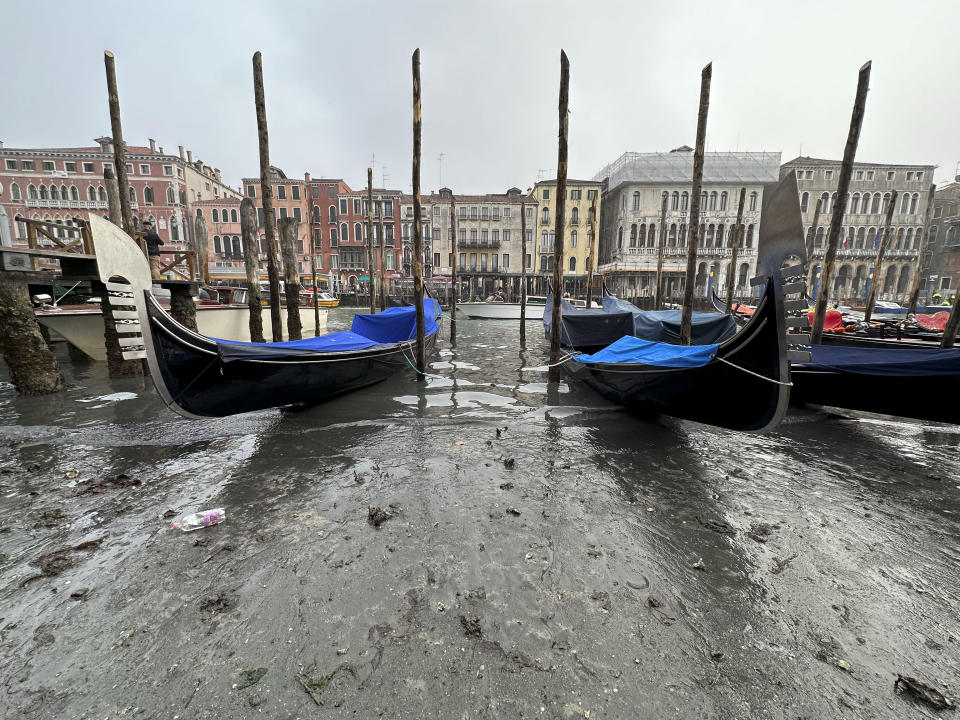 Gondolas are docked along a canal with a low water level during a low tide in Venice, Italy, Saturday, Feb. 18, 2023. (AP Photo/Luigi Costantini)