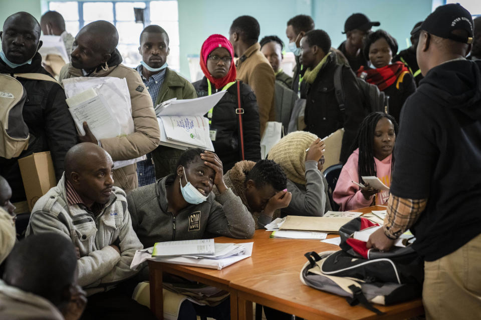 Electoral workers line up to have their ballot boxes stored and results tallied at a collection and tallying center in Nairobi, Kenya Wednesday, Aug. 10, 2022. Kenyans are waiting for the results of a close but calm presidential election in which the turnout was lower than usual. (AP Photo/Ben Curtis)