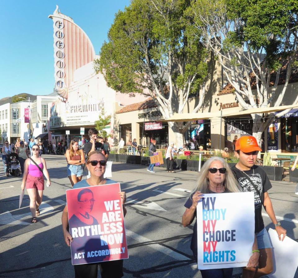 Julie Rutledge, left, and Jeanne James hold signs on Monterey Street near the Fremont Theater.