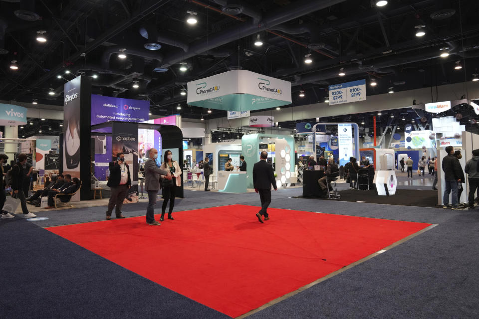 People walk across an empty booth spot during the CES tech show Thursday, Jan. 6, 2022, in Las Vegas. (AP Photo/Joe Buglewicz)