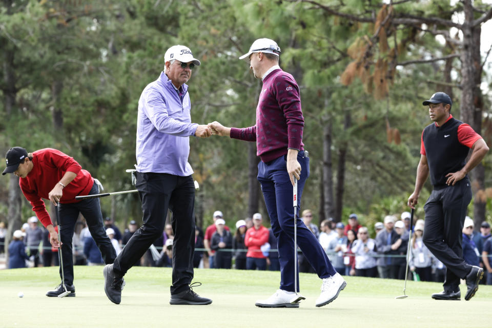 Mike Thomas, center left, and Justin Thomas, center right, fist bump after Mike's putt on the 3rd hole during the final round of the PNC Championship golf tournament Sunday, Dec. 18, 2022, in Orlando, Fla. Charlie Woods, left, lines up a putt as Tiger Woods, right, watches. (AP Photo/Kevin Kolczynski)