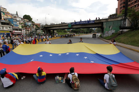 Opposition supporters hold a Venezuelan national flag as they block a highway, during a protest against Venezuelan President Nicolas Maduro's government in Caracas, Venezuela May 15, 2017. REUTERS/Christian Veron