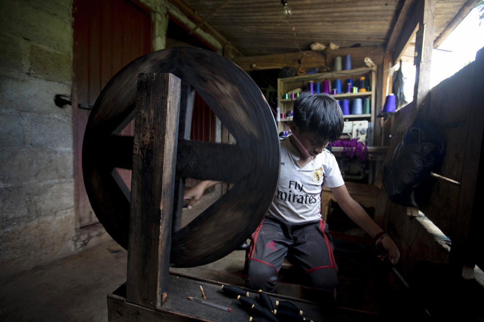 Juan Gabriel Vazquez spins thread at his home while schools are closed amid the new coronavirus pandemic in the community of Nuevo Yibeljoj, Chiapas state, Mexico, Friday, Sept. 11, 2020. Since schools closed in March, the 11-year-old is one of 12 siblings who work in the coffee fields daily instead of just the weekends, while his father helps them with school work dropped off by teachers. (AP Photo/Eduardo Verdugo)