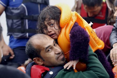 A Syrian refugee lifts his daughter from an overcrowded dinghy after crossing part of the Aegean Sea from Turkey to the Greek island of Lesbos September 23, 2015. REUTERS/Yannis Behrakis