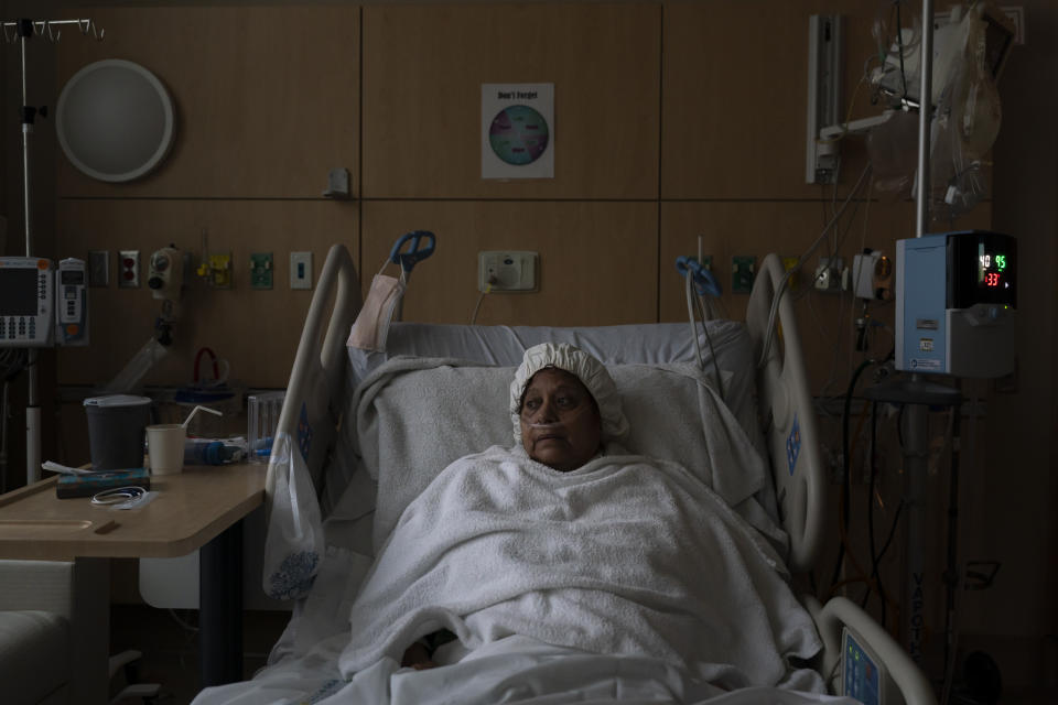 Natalie Balli, 71, looks out the window while resting in her bed in a COVID-19 unit at Providence Holy Cross Medical Center in Los Angeles, Monday, Dec. 13, 2021. Balli and her twin sister were admitted to the hospital on the same day, a few days after their Thanksgiving gathering. (AP Photo/Jae C. Hong)