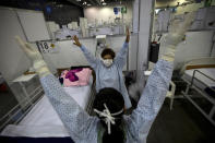 FILE - In this March 11, 2021 file photo, directed by a nurse, a COVID-19 patient, back center, stretches her arms as part of a fitness program in a field hospital built inside the Citibanamex convention center in Mexico City. Mexico City's government announced on Friday, May 7, 2021 that public hospitals dedicated to fighting COVID-19 is experiencing its lowest rate occupancy of the pandemic and the city is slightly easing some restrictions, more than three months after COVID-19 infections peaked in the Mexican capital. (AP Photo/Fernando Llano, File)