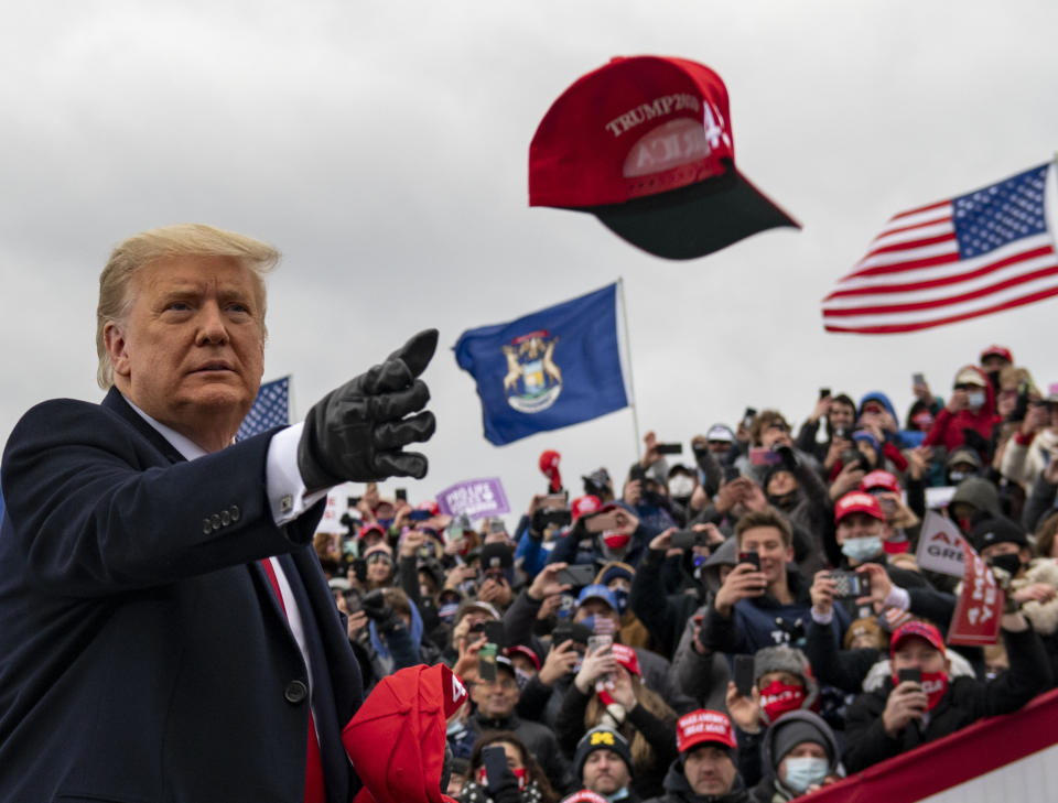 President Donald Trump tosses a cap during a campaign stop in Waterford Township, Mich., Friday Oct. 30, 2020. (Nicole Hester/Ann Arbor News via AP)
