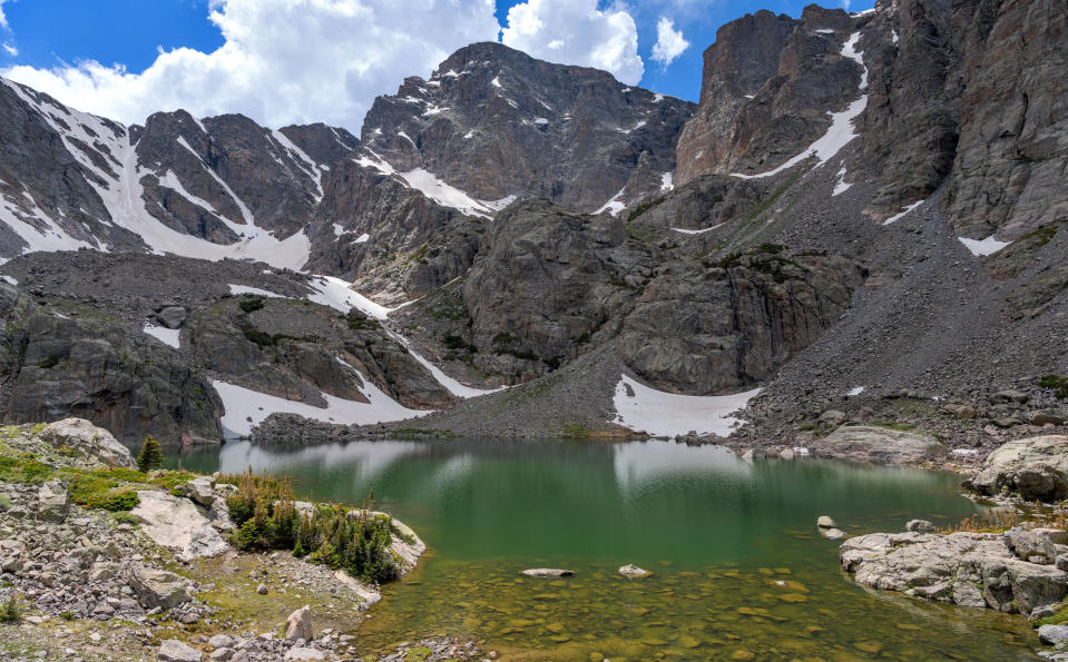 A closeup view of colorful Sky Pond, with Taylor Peak and Taylor Glacier towering at shore, on a calm Summer day. Rocky Mountain National Park, Colorado, USA.