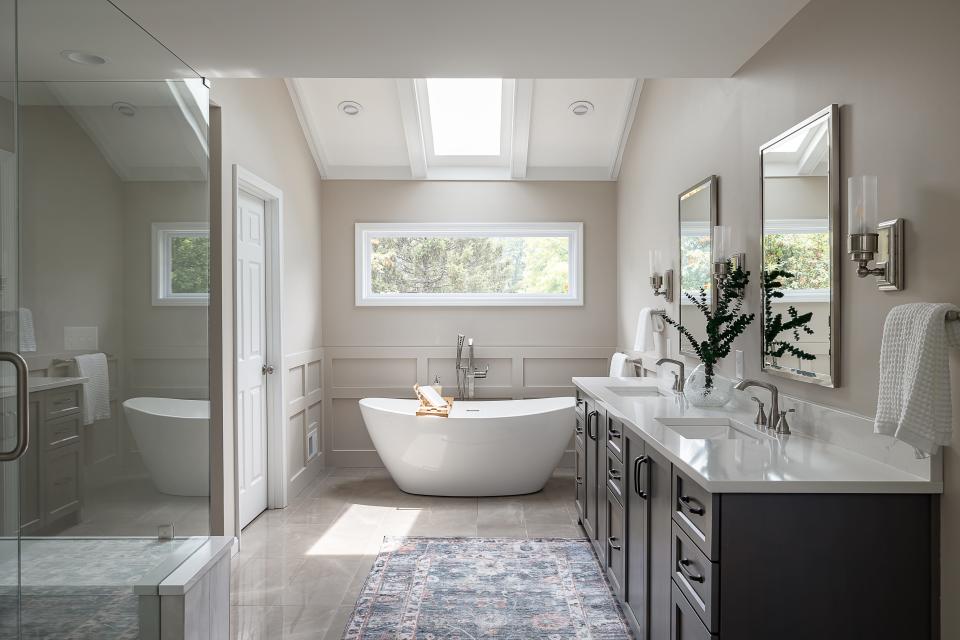 Natural light flows through the primary bath via a window and skylight over the soaking tub at this remodeled home in Plainview.