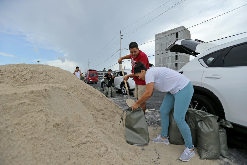 Farah and Max Cicardini fill sand bags at the parking of the Big Easy Casino on Friday, Aug. 30, 2019 in Hallandale Beach, Fla., as they prepare for Hurricane Dorian.