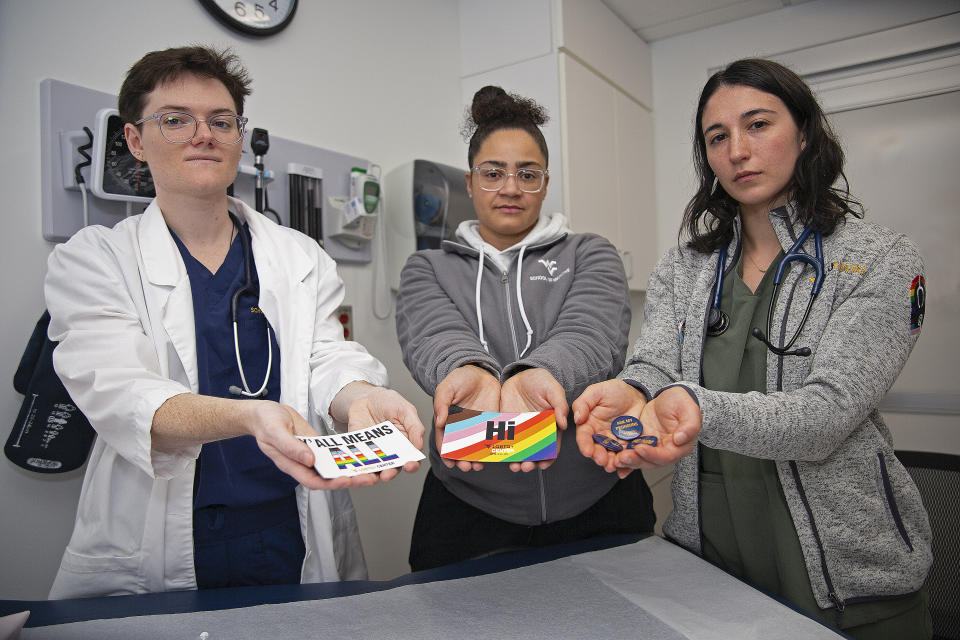 West Virginia University students El Didden, Bri Caison and Lia Farrell hold materials from the Rainbow Coats on Wednesday, March 8, 2023, in Morgantown, W.Va. (AP Photo/Kathleen Batten)