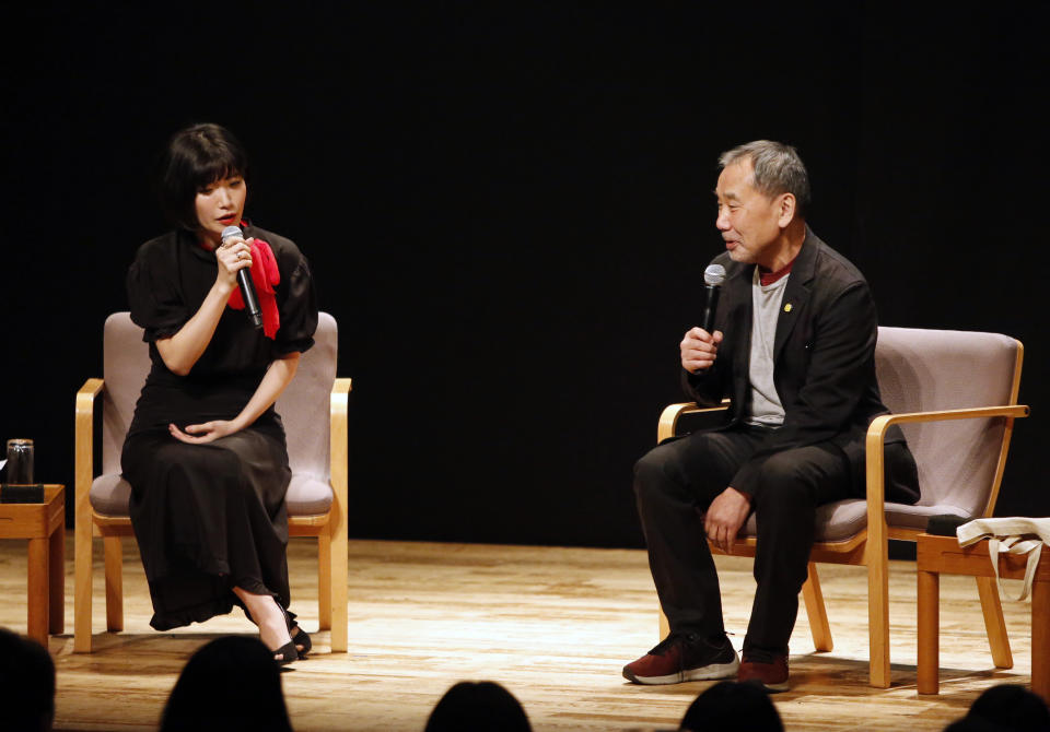 In this photo provided by Shinchosa, author Haruki Murakami, right, speaks on stage next to author Mieko Kawakami in Tokyo, Tuesday, Dec. 17, 2019. A monkey that confesses he steals women's identity cards, causing them to temporarily forget who they are, stars as author Haruki Murakami marks 40 years since his debut as a novelist with his first public reading in Japan in nearly a quarter century. Now 70 and one of the world’s most popular and acclaimed novelists, Murakami debuted with “Hear the Wind Sing” in 1979, four years after he began writing while running a jazz bar in Tokyo. (Shinchosa via AP)