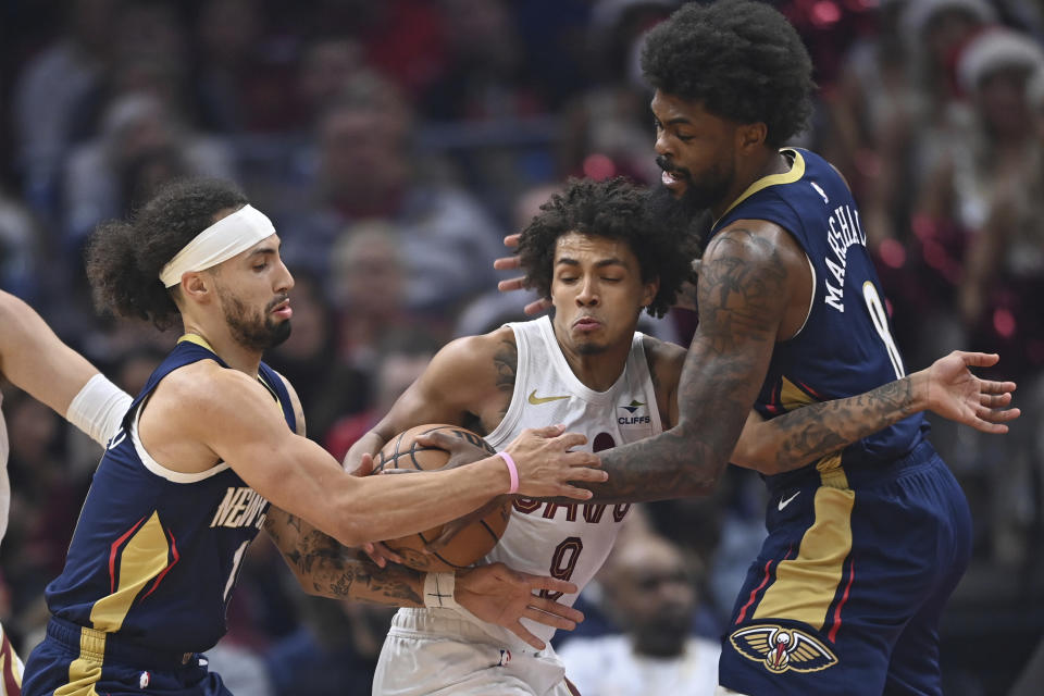 New Orleans Pelicans guard Jose Alvarado, left, rips the ball away from Cleveland Cavaliers guard Craig Porter as he was being defined by forward Naji Marshall in the first half of an NBA basketball game Thursday, Dec. 21, 2023, in Cleveland. (AP Photo/David Dermer)