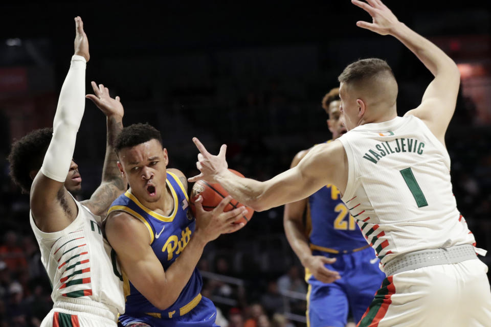 Pittsburgh guard Trey McGowens, center, is defended by Miami guards Chris Lykes, left, and Dejan Vasiljevic (1) during the first half of an NCAA college basketball game, Sunday, Jan. 12, 2020, in Coral Gables, Fla. (AP Photo/Lynne Sladky)