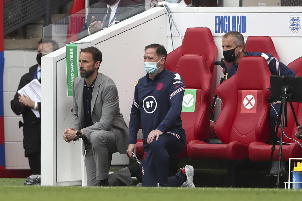 England's coach Gareth Southgate, left, along with technical staff and substitutes take a knee before the international friendly soccer match between England and Romania in Middlesbrough, England, Sunday, June 6, 2021. (AP Photo/Scott Heppell, Pool)