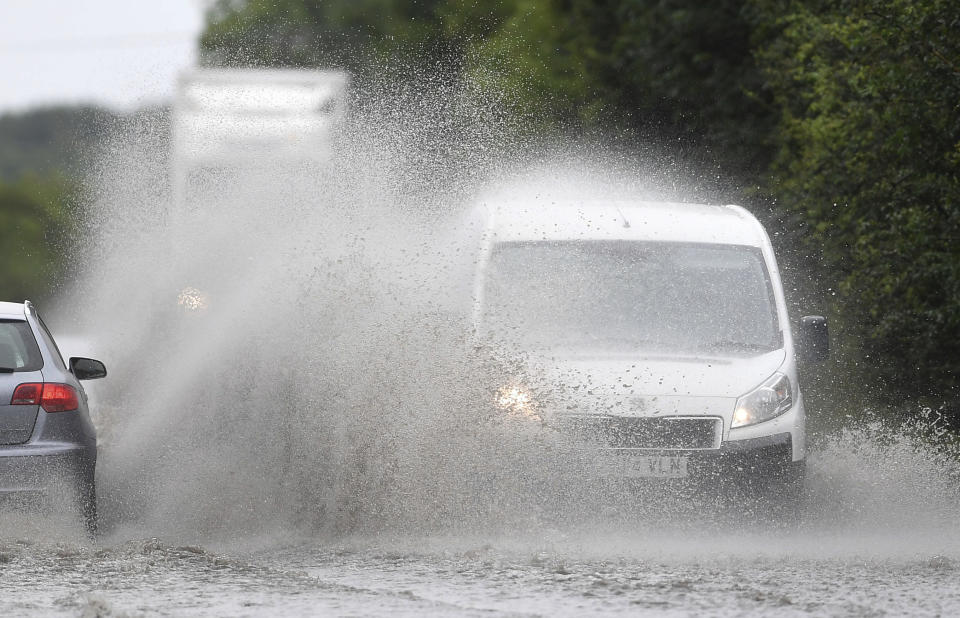 Cars make their way through standing water on a main road near Peterborough, England, after heavy rain fell overnight, Sunday July 28, 2019.  Weather forecasters have issued a yellow weather warning for rain across and possible travel disruption in many parts of England on Sunday. (Joe Giddens/PA via AP)