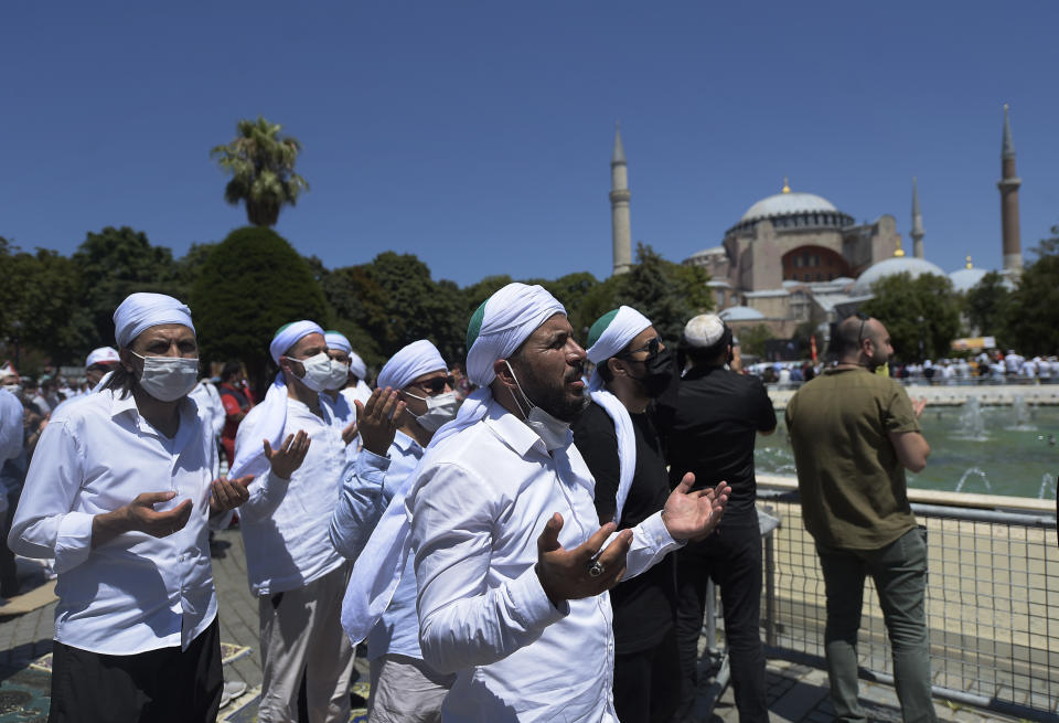 Muslims pray during Friday prayers at the historic Sultanahmet district of Istanbul, near the Byzantine-era Hagia Sophia, background, Friday, July 24, 2020. Thousands of Muslim faithful surrounded Istanbul's landmark monument Friday to take part in the first prayers in 86 years at the structure that was once Christendom's most significant cathedral and the "jewel" of the Byzantine Empire then a mosque and museum before its re-conversion into a Muslim place of worship. The conversion of the edifice, has led to an international outcry. (AP Photo/Yasin Akgul)