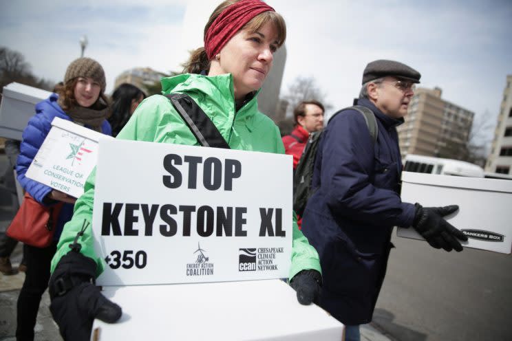 <i>[Activists carry signs and petition boxes as they march to the State Department for a rally to protest against the Keystone XL pipeline March 7, 2014 in Washington, DC. (Photo by Alex Wong/Getty Images)]</i>