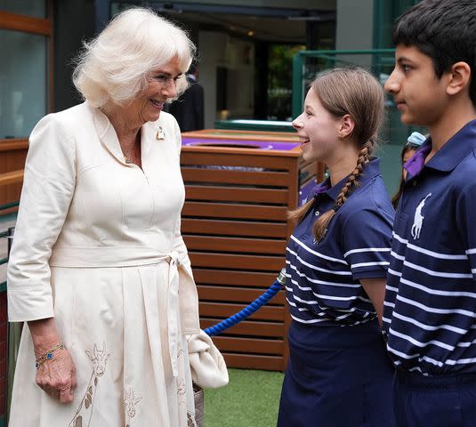 <p>JORDAN PETTITT/POOL/AFP via Getty</p> Queen Camilla meets a young ball girl and ball boy at Wimbledon on July 10, 2024.