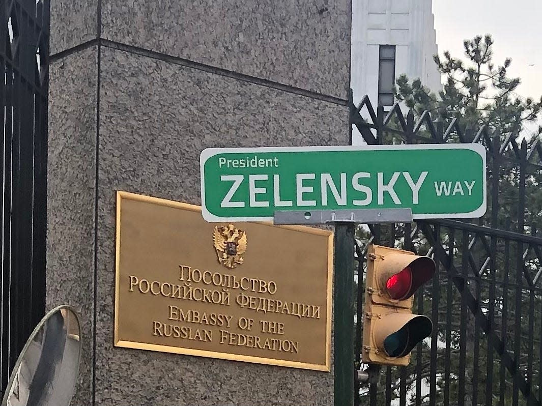 A "President Zelensky Way" sign placed in front of a Russian embassy sign.