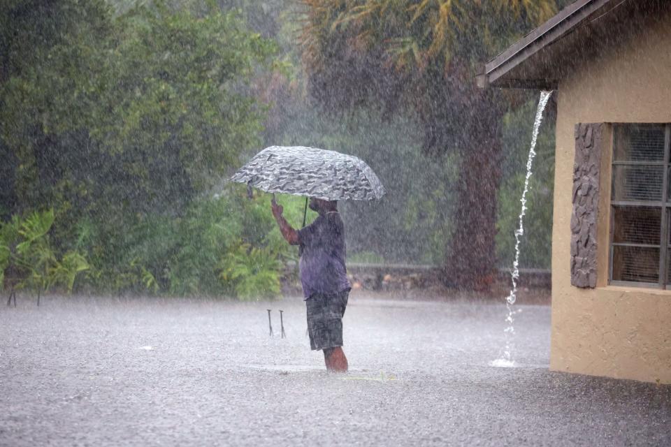 A man stops to take pictures of his flooded neighborhood along Southwest Third Street and Southwest Fourth Avenue in Dania Beach on Wednesday, April 12, 2023.