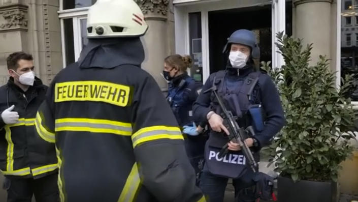 In this image from a video shows armed police officers and rescue workers speaking together near the scene of an incident in the city of Trier, Germany, Tuesday, Dec 1, 2020. German police say two people have been killed and several others injured in the southwestern German city of Trier when a car drove into a pedestrian zone. Trier police tweeted that the driver had been arrested and the vehicle impounded. (NonstopNews via AP)