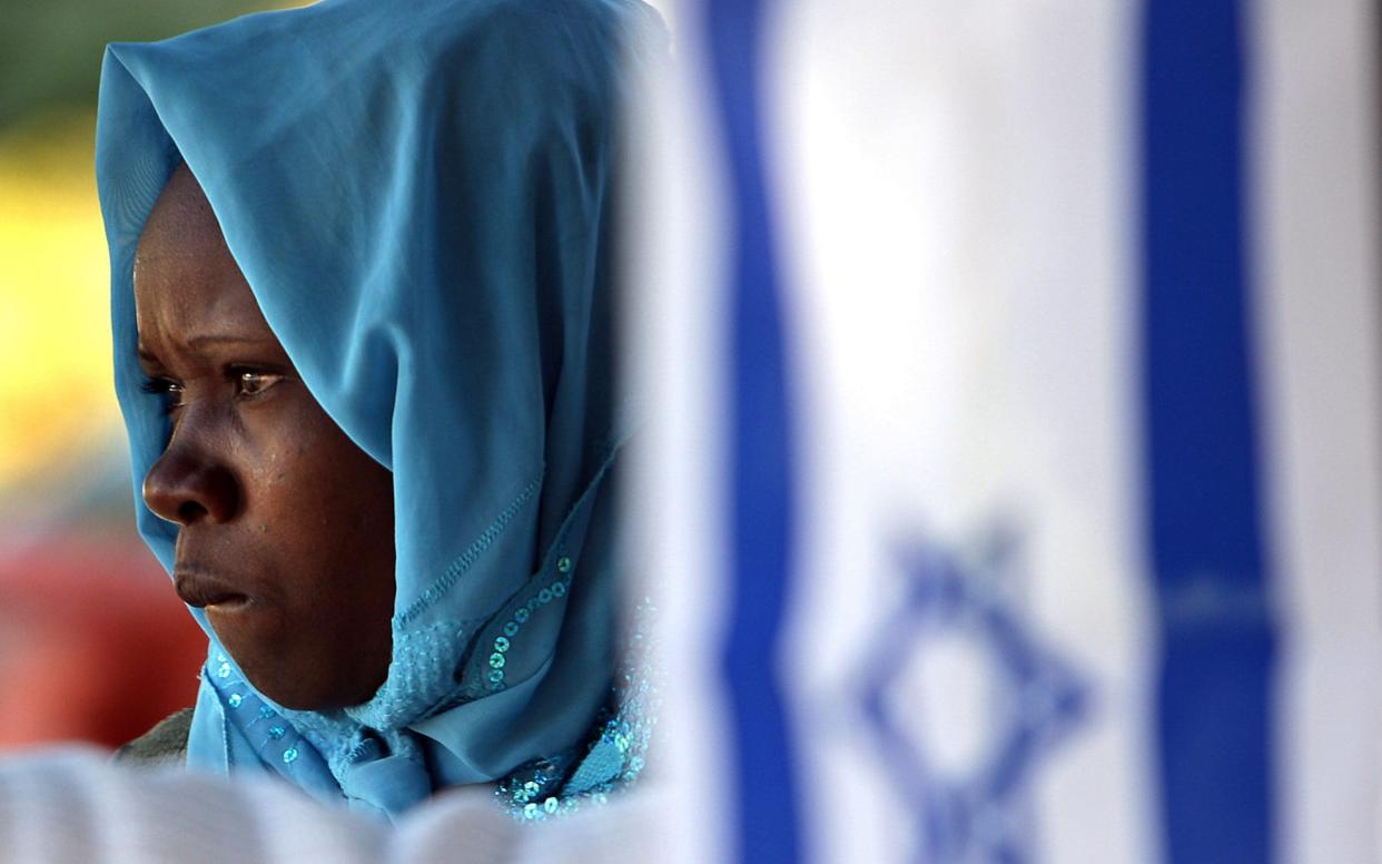 A Sudanese refugee stands behind an Israeli flag - AFP