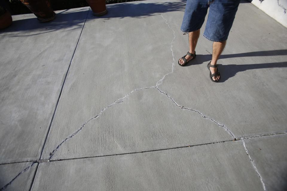 Homeowner Gary Gless stands by cracks in cement in his backyard in Los Angeles, California