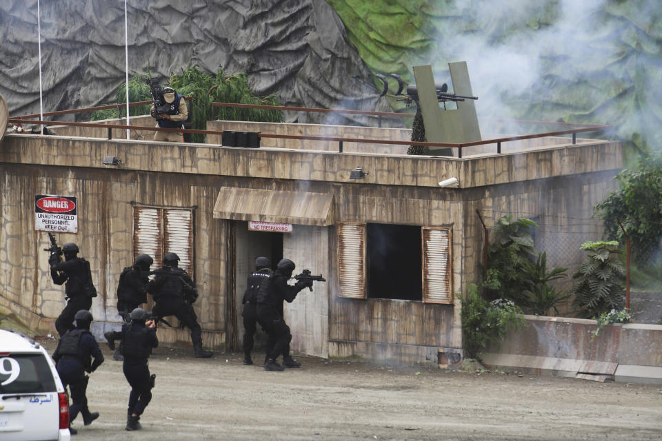 Troops raid a building during a military demonstration at the International Defense Exhibition and Conference in Abu Dhabi, United Arab Emirates, Sunday, Feb. 17, 2019. The biennial arms show in Abu Dhabi comes as the United Arab Emirates faces increasing criticism for its role in the yearlong war in Yemen. (AP Photo/Jon Gambrell)