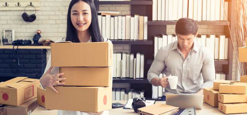 Two young people packing up boxes for shipping.