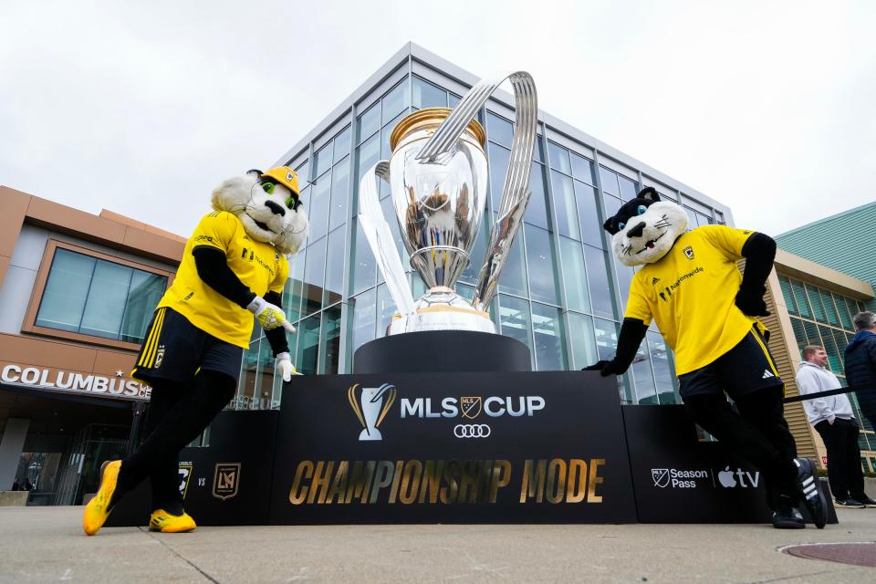 Dec 6, 2023; Columbus, OH, USA; Columbus Crew mascots, Crew Cat and SC, stand in front of a giant replica of the Philip F. Anschutz Trophy outside the Greater Columbus Convention Center in the Short North during a Major League Soccer event to celebrate the arrival of the 2023 MLS Cup presented by Audi in Columbus, Ohio. Mandatory Credit: Adam Cairns-USA TODAY Sports