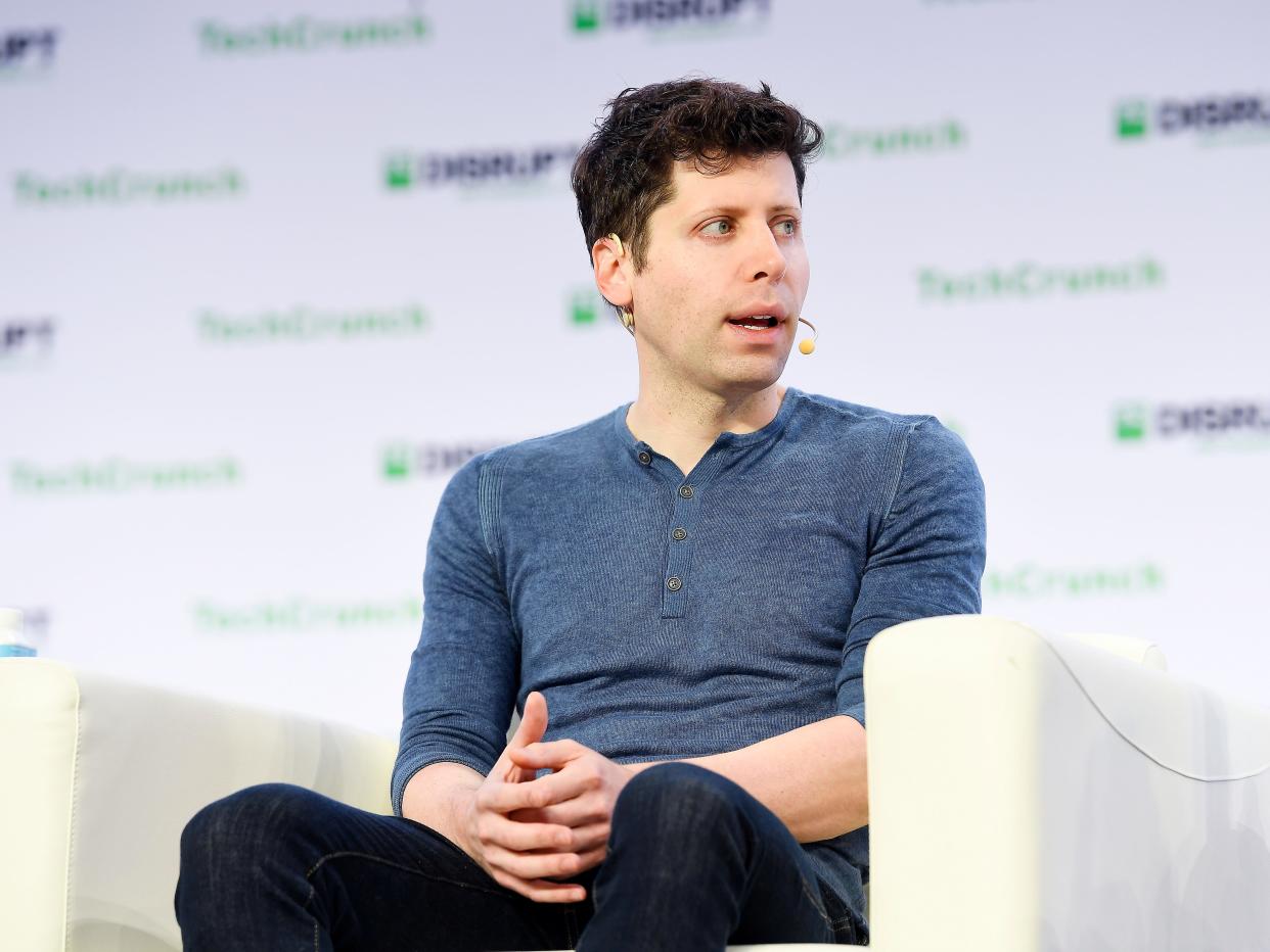 Sam Altman sitting in a chair at a conference.