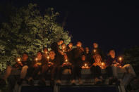 People hold candles for the victims near the Vladislav Ribnikar school in Belgrade, Serbia, Wednesday, May 3, 2023. Police say a 13-year-old who opened fire at his school drew sketches of classrooms and made a list of people he intended to target. He killed eight fellow students and a school guard before being arrested. (AP Photo/Armin Durgut)