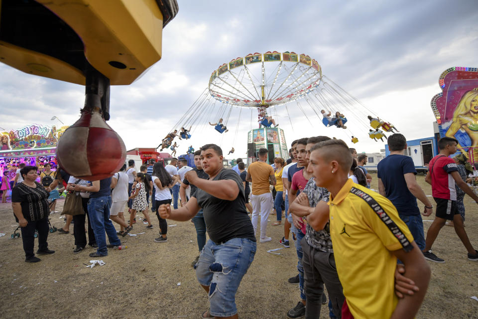 In this picture taken Saturday, Sept. 14, 2019, a man tests his strength at a boxing power punch machine at an autumn fair in Titu, southern Romania. Romania's autumn fairs are a loud and colorful reminder that summer has come to an end and, for many families in poorer areas of the country, one of the few affordable public entertainment events of the year. (AP Photo/Andreea Alexandru)