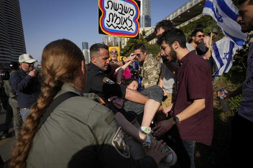 Israeli police scuffle with protesters as they try to block a main road to protest against plans by Prime Minister Benjamin Netanyahu's new government to overhaul the judicial system, in Tel Aviv, Israel, Wednesday, March 1, 2023. (AP Photo/Ohad Zwigenberg)