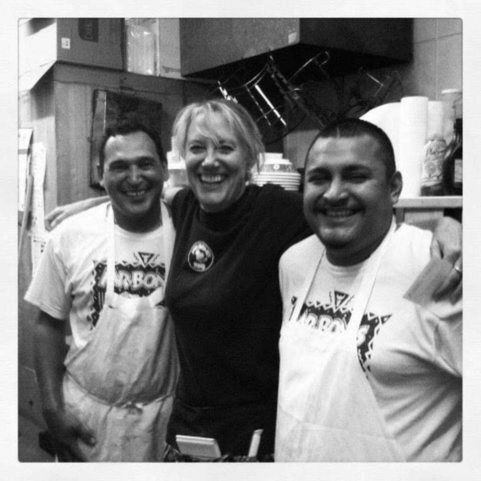 Mr. Bones BBQ co-owner Charlotte Mansur (middle) poses with two employees inside the restaurant’s kitchen.