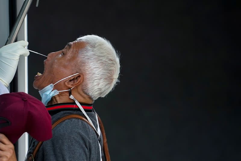 FILE PHOTO: A healthcare worker takes a nasal swab sample from a local resident for a COVID-19 test in Bangkok