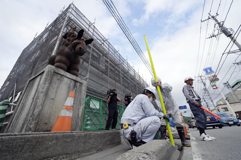 Workers set up a barricade near the Lawson convenience store, where the popular photo spot framing a picturesque view of Mount Fuji in the background Tuesday, April 30, 2024, at Fujikawaguchiko, Yamanashi Prefecture, central Japan. (AP Photo/Eugene Hoshiko)