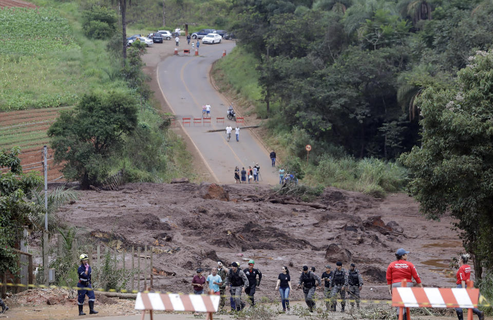 Policemen and rescue personnel work at a blocked road after a dam collapsed, in Brumadinho, Brazil, Saturday, Jan. 26, 2019. Searchers flying in helicopters and rescuers laboring in deep mud uncovered more bodies Saturday afternoon near the dam in Brumadinho. (AP Photo/Andre Penner)