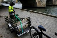 An employee of bicycle sharing service Lime patrols to fish abandoned electric scooters out of the River Seine in Paris