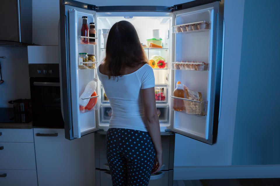 Rear View Of Young Woman Looking In Fridge At Kitchen