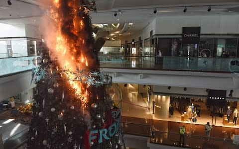  Christmas tree burns after protesters set fire to it at Festival Walk shopping mall in Kowloon Tong - Credit: MIGUEL CANDELA/EPA