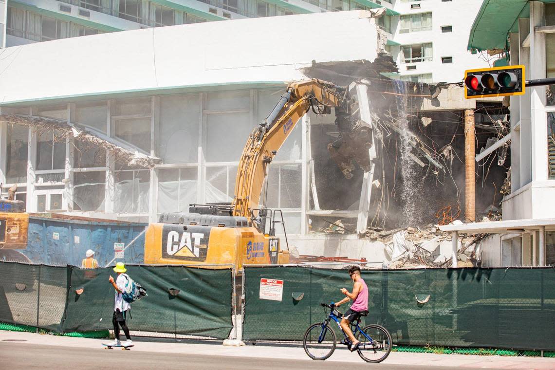 People skateboard and walk on Collins Avenue as crews work to demolish the Deauville Beach Resort in Miami Beach on Sept. 6, 2022.