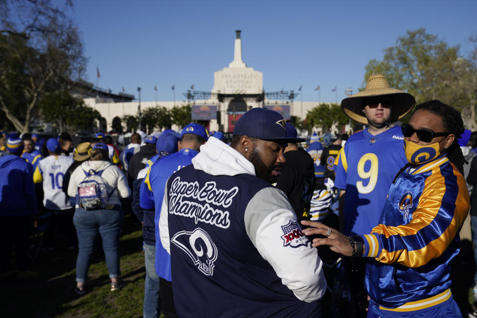 A fan admires the logo on a jacket from Super Bowl 34, which was won by the St. Louis Rams, during a gathering near Los Angeles Memorial Coliseum before the Los Angeles Rams' victory parade, Wednesday, Feb. 16, 2022, in Los Angeles, following the Rams' win Sunday over the Cincinnati Bengals in the NFL Super Bowl 56 football game. (AP Photo/Marcio Jose Sanchez)