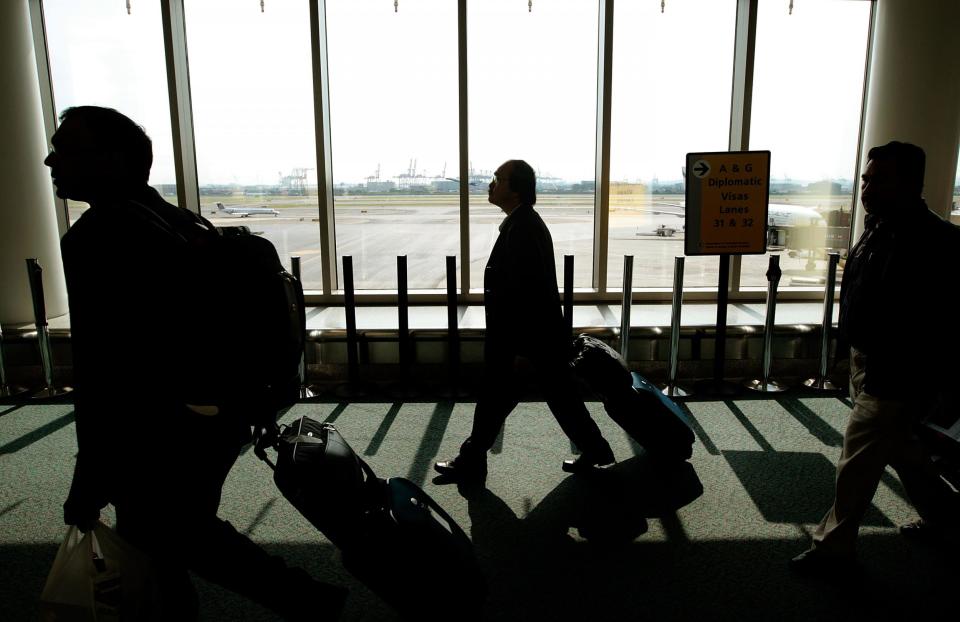 Travellers with bags walk toward the passport control line at Newark International Airport (Getty Images)