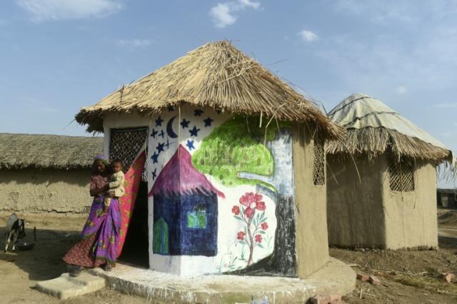 Une femme et son enfant devant leur hutte conçue pour résister aux inondations, le 8 avril 2023 à Tando Allahyar, au Pakistan