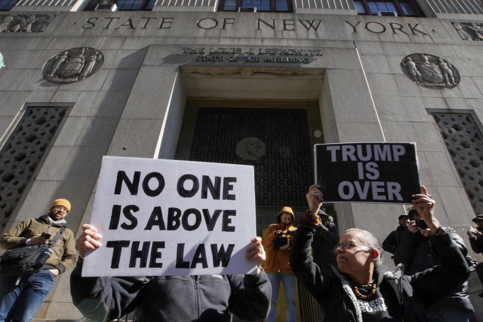People hold up posters as part of a protest in front of the courthouse ahead of former President Donald Trump's anticipated indictment on Monday, March 20, 2023, in New York. (AP Photo/Eduardo Munoz Alvarez)