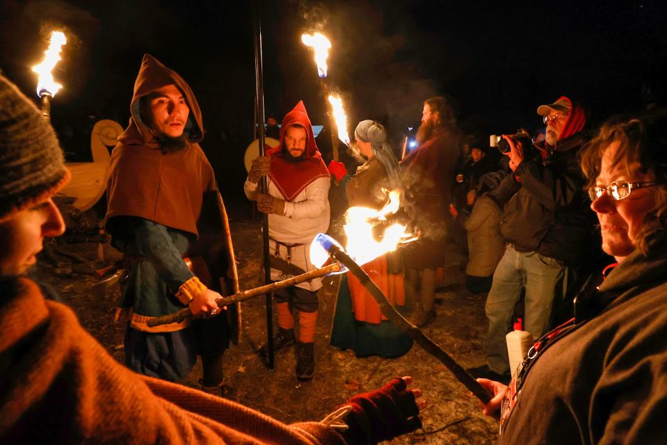 Christian Ortiz, 38, of Hamilton, Ohio, second from left, and a member of the Viking Vulksgaard, watch as others get their torches going in order to light the Viking ship on fire during the opening ceremony of the Michigan Nordic Fire Festival at the Eaton County Fairgrounds in Charlotte on Friday, Feb. 24, 2023. The burning of the Viking ship has been a tradition to open the festival for the past six years.