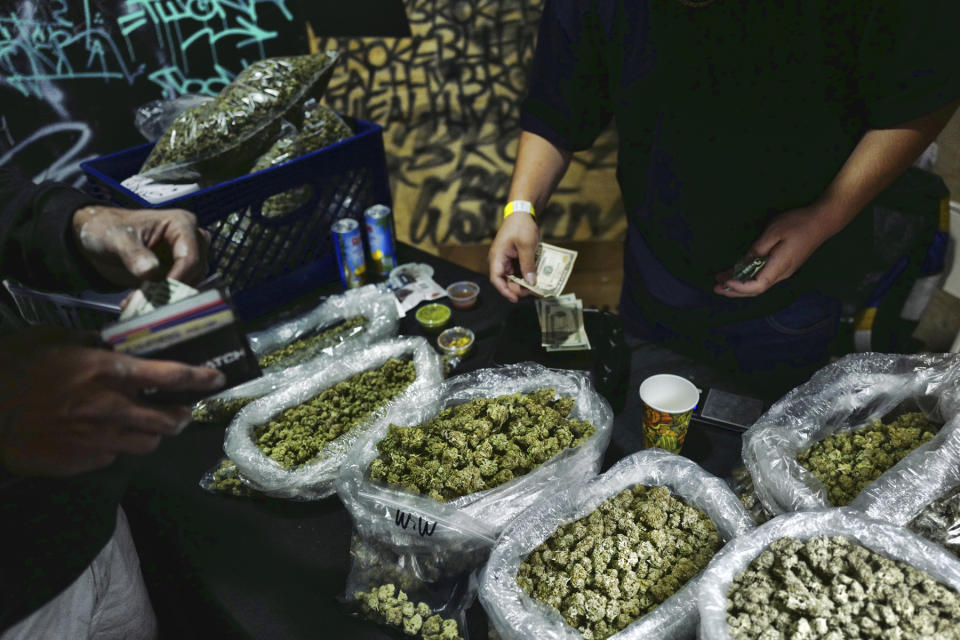 FILE - In this April 15, 2019, file photo, a vendor makes change for a marijuana customer at Rev-Up a cannabis marketplace in Los Angeles. An alliance of large cannabis businesses in the growing global marketplace has a message for the public: We're good corporate citizens. The 45-member Global Cannabis Partnership that includes Canopy Growth Corp. and other major companies issued guidelines Tuesday, June 18, 2019, aimed at minimizing greenhouse gas emissions and promoting ethical conduct and responsible pot use. (AP Photo/Richard Vogel)